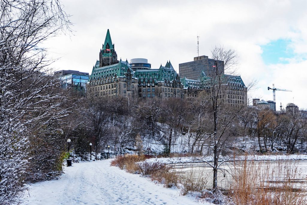 view of the parliament building in Ottawa with a snowing trail and trees in front of it