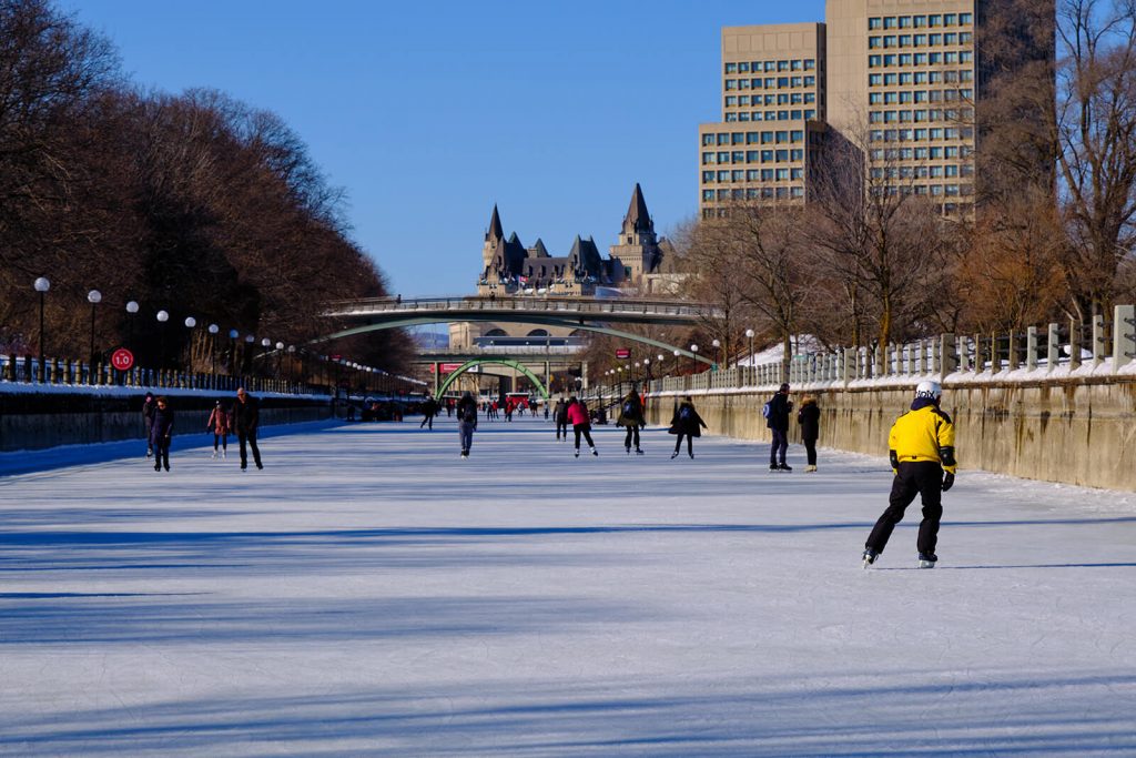 People skating on the Rideau Canal with the Parliament building in the background