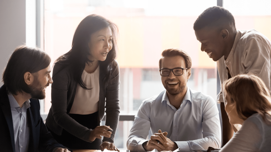 5 people wearing professional attire sitting around a table talking