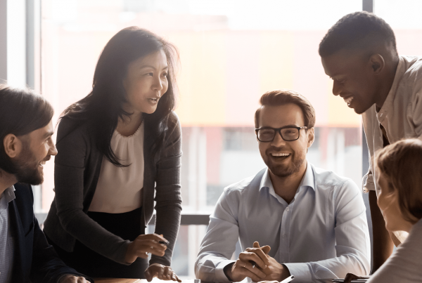 5 people wearing professional attire sitting around a table talking