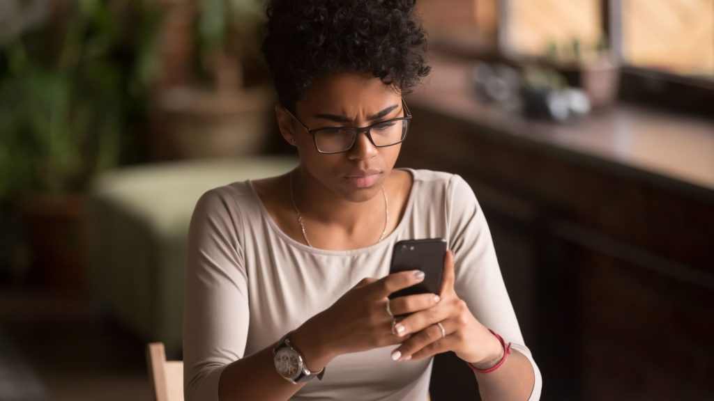 A woman looking at her phone pensively.