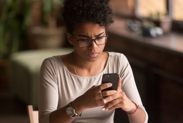 A woman looking at her phone pensively.