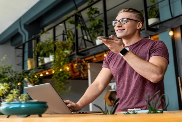 Male speaks on his cell phone with a laptop in front of him, looking positive and professional