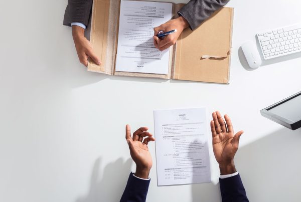 aerial view above a desk showing contracts on the desk with two sets of hands above them.