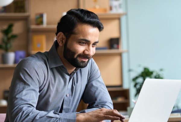 a man in professional attire typing on a laptop