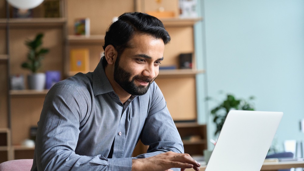 a man in professional attire typing on a laptop
