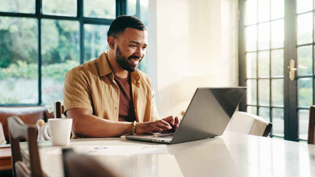 a man sitting at a desk typing on a laptop