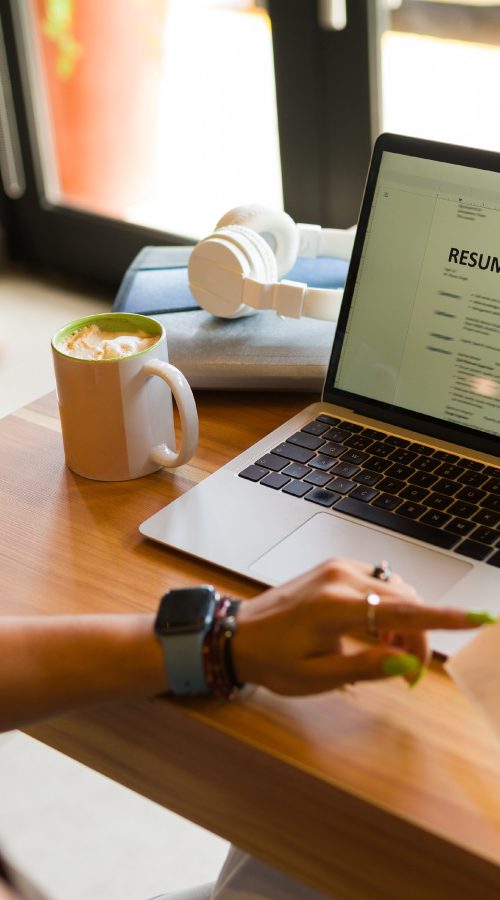 A women sitting at a desk with a laptop holding a resume in her hand