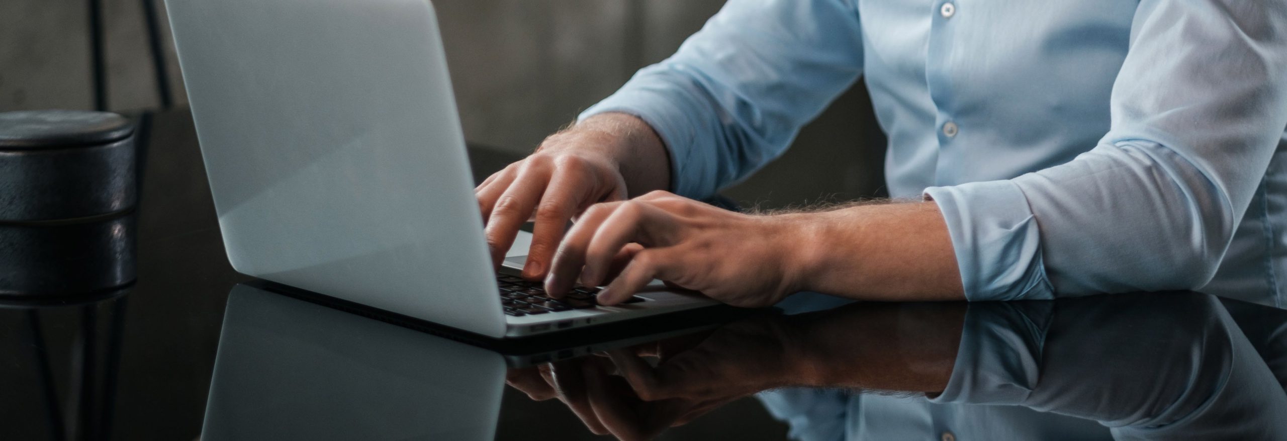 Hands typing on a laptop at a dark desk