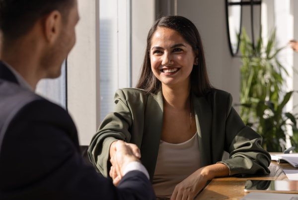 A woman in professional attire shaking the hand of a man in a suit