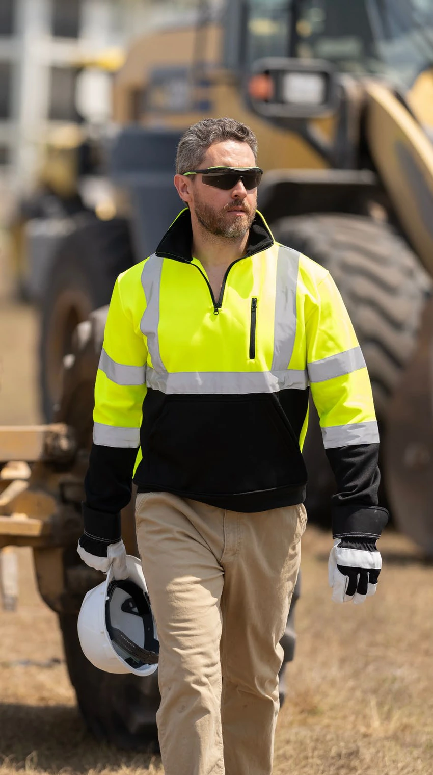 A site worker in a high-visibility jacket walking across a construction site