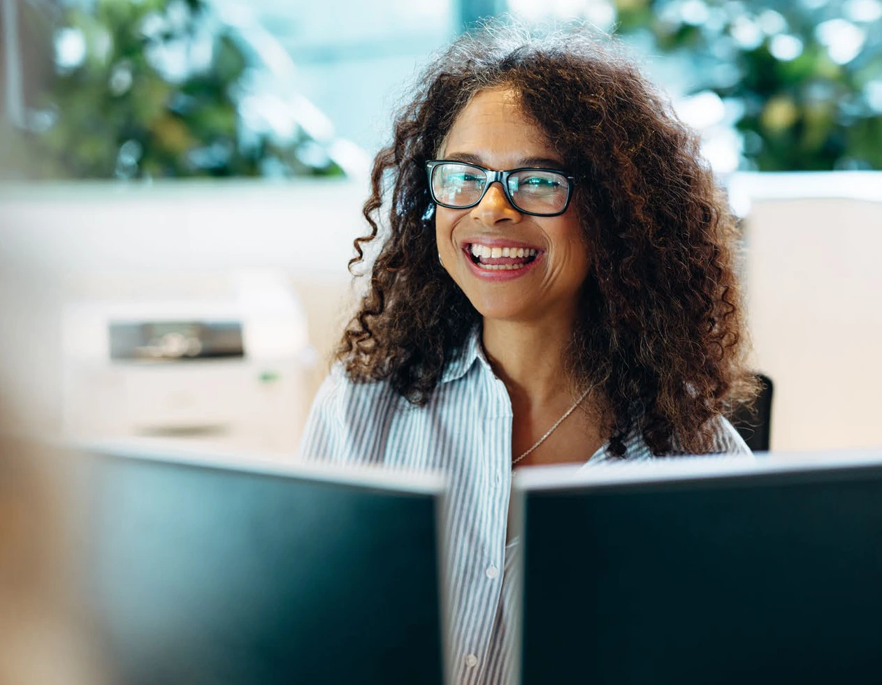 A smiling office professional in glasses working at a computer