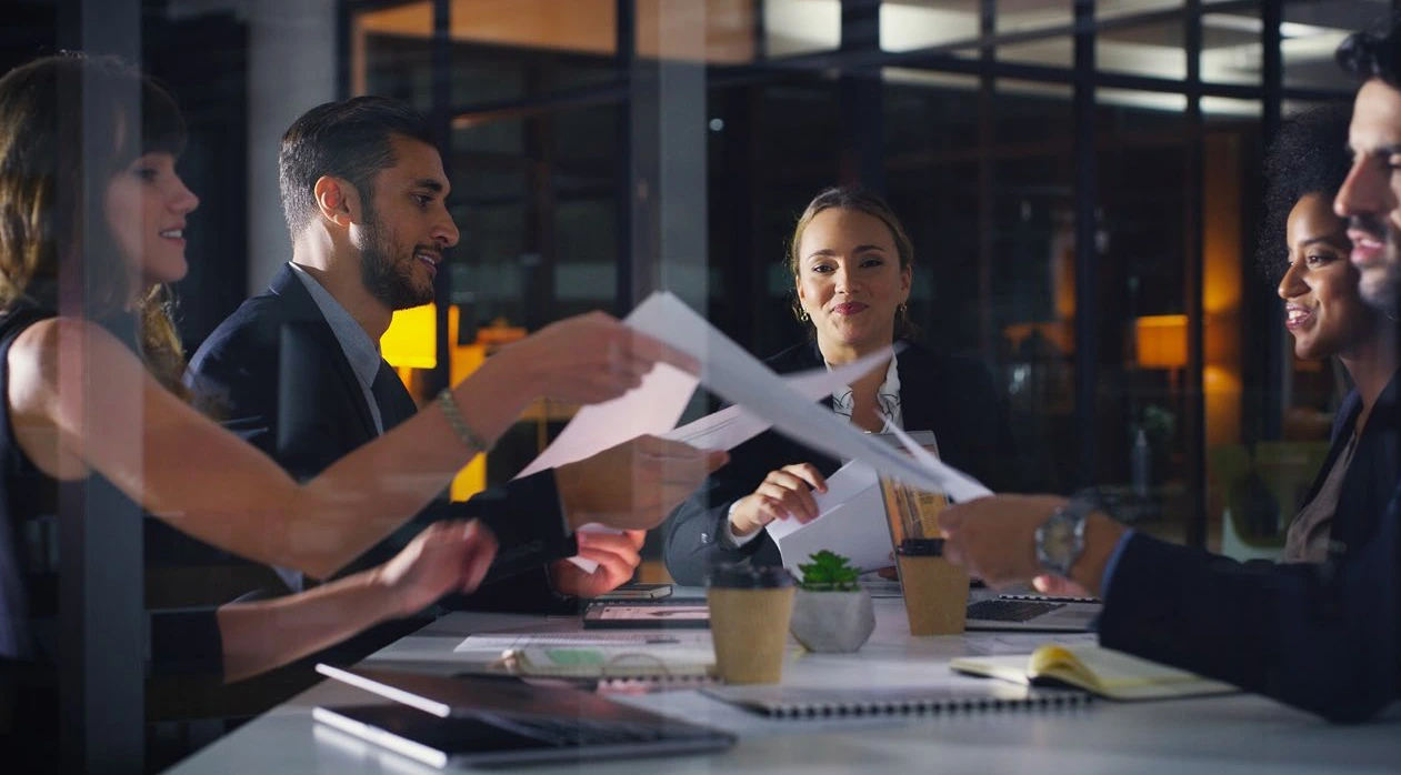 Colleagues passing documents across a table during a meeting