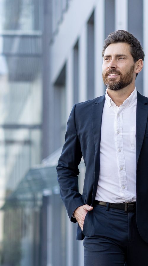 A man wearing a suit walking outside next to a commercial building